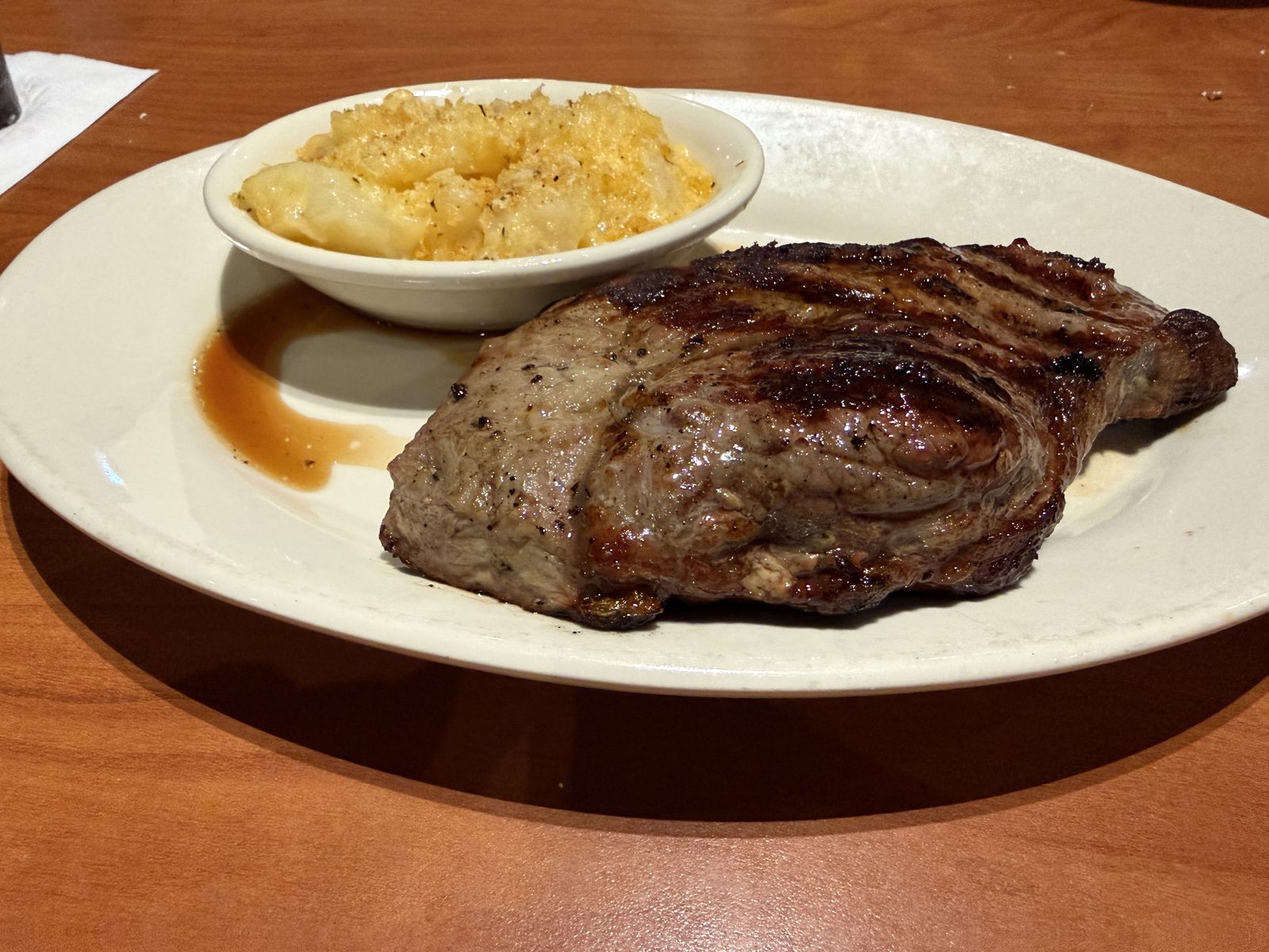 One of the steaks that came out — the ribeye, a $7 upcharge over the base entrées, and the thinner, drier plate of the two.