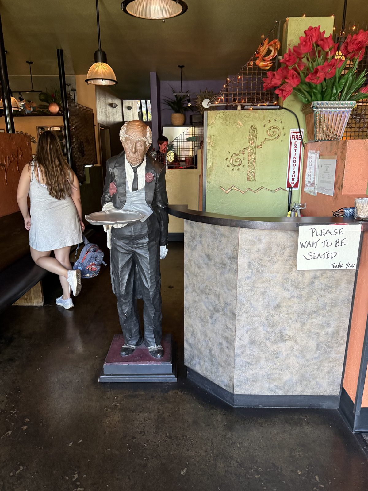 The host stand — a waiter statue that's been greeting people here for who knows how long.