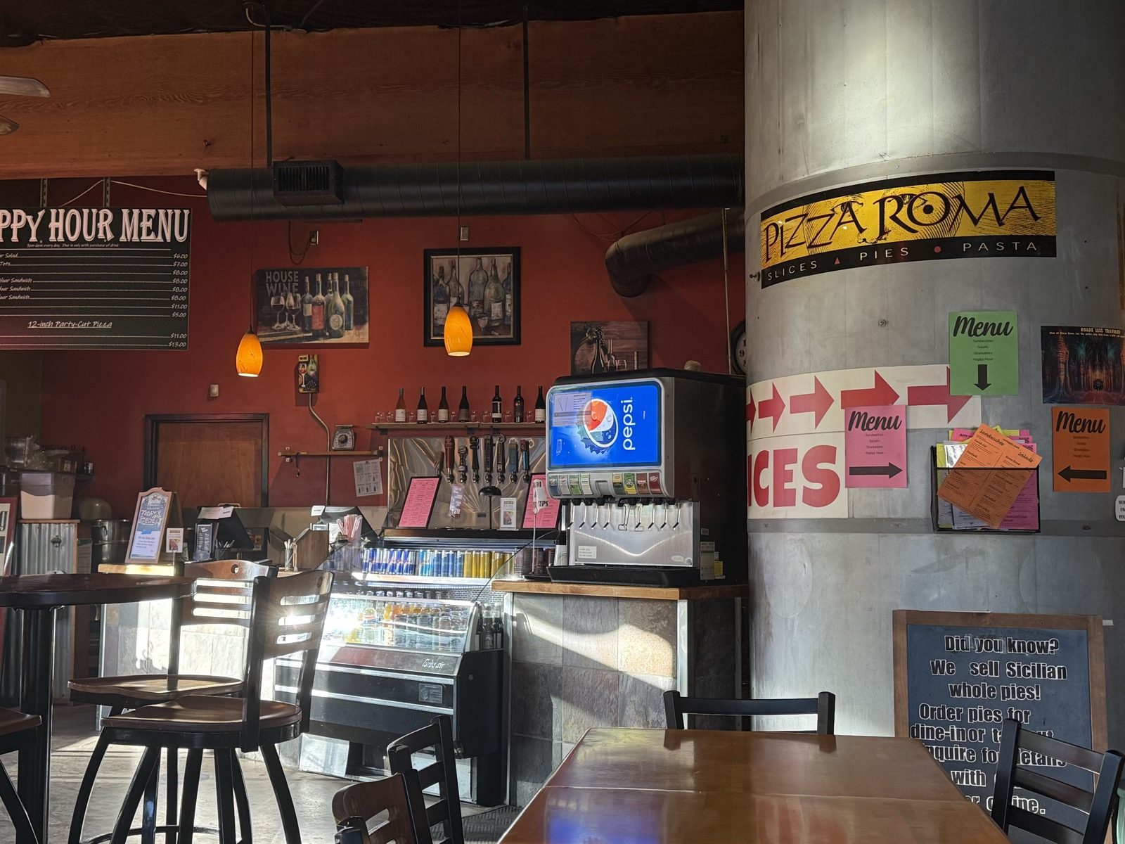 Slices, pies, pasta — and a happy hour list on the chalkboard next to it.