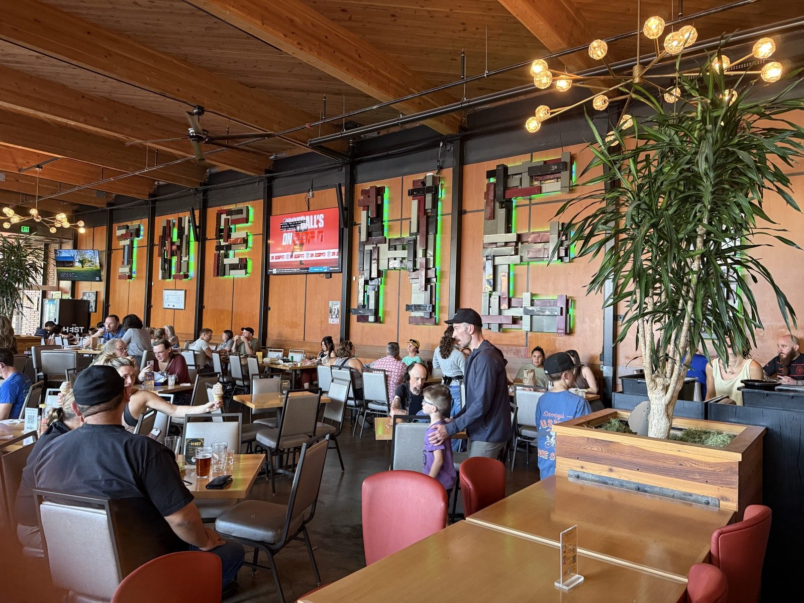 Indoor seating under a wood-beamed ceiling, with HEIST spelled out in salvaged metal on the wall.