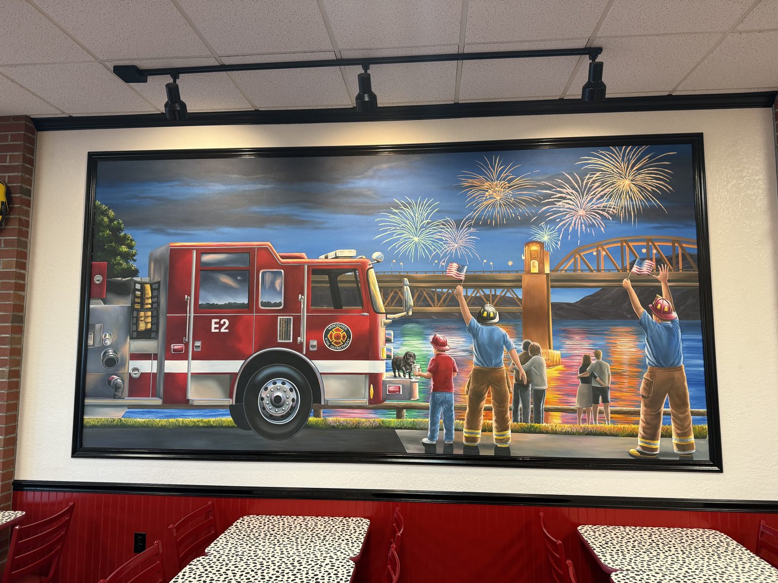 The dining room's mural — a Vancouver Fire Department engine, the Interstate Bridge, and fireworks over the Columbia. The theming goes well past the napkins.