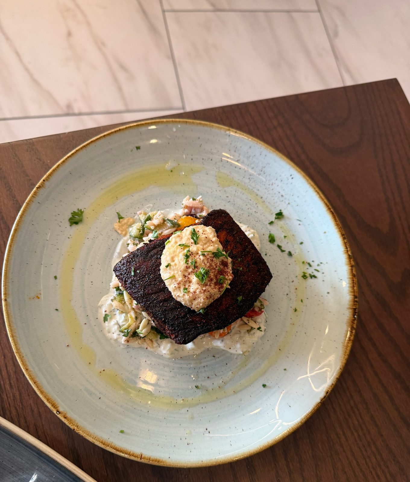 The Mediterranean Salmon — blackened crust, orzo salad, a swipe of hummus.