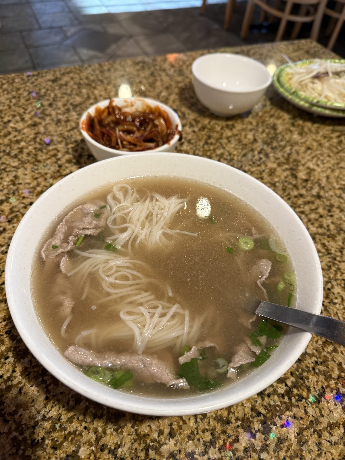 The bowl, the spoon, and the cup of hành dấm off to the side — everything the bite above needs.