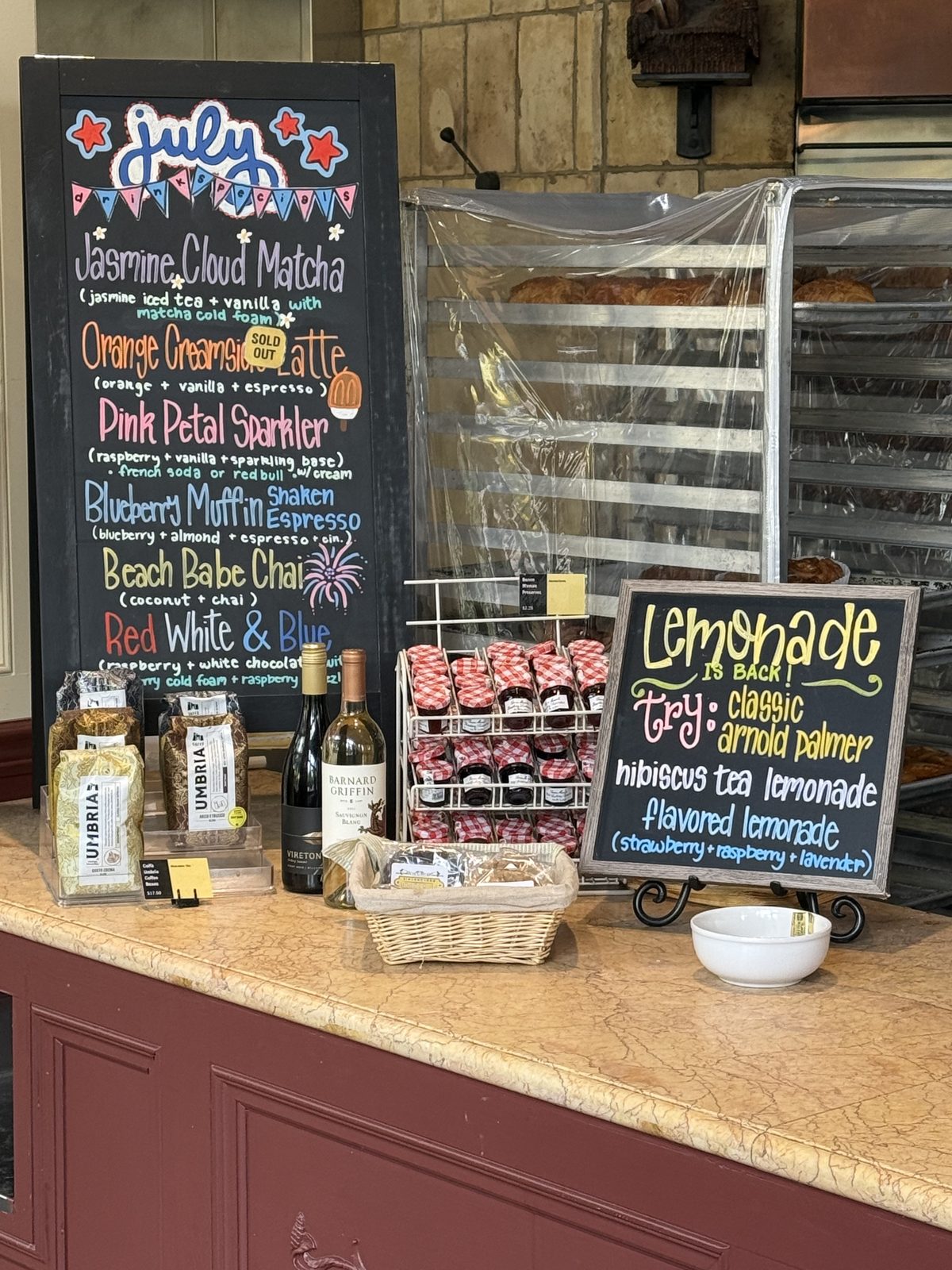 The July specials board, chalked by hand, next to the retail jam and wine.